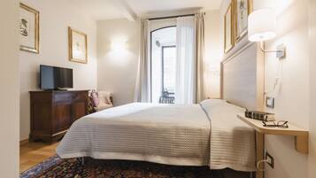 Un dormitorio con cama, televisor, escritorio y ventana con cortinas.
