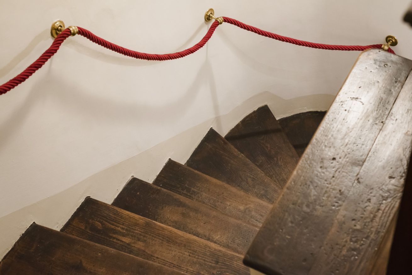 A wooden staircase with a red rope barrier.