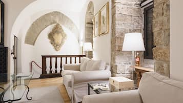 A cozy living room with a stone wall, a wooden staircase, and a white sofa.