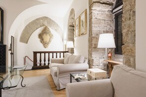 Un salón acogedor con una pared de piedra, una escalera de madera y un sofá blanco.