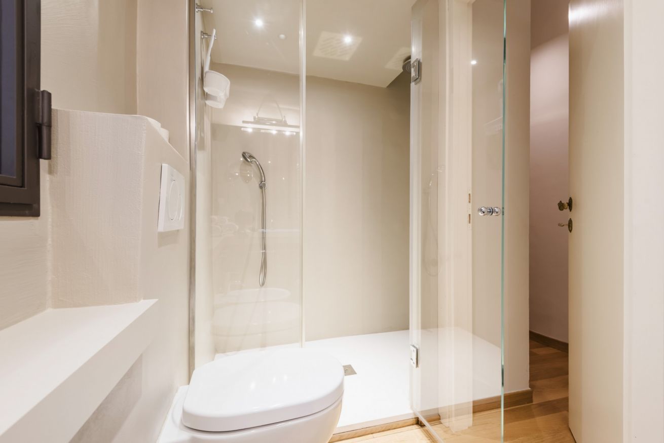 Un bagno moderno con doccia vetrata, un water bianco e un portasciugamani a vista.