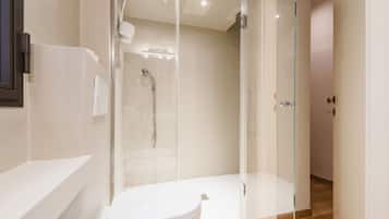Un bagno moderno con doccia vetrata, un water bianco e un portasciugamani a vista.