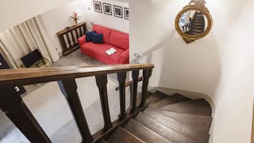 A wooden staircase with a red couch and a wall-mounted mirror in a living area.
