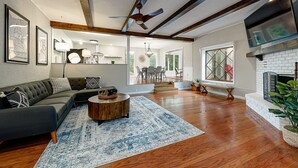 A spacious living room with a sectional sofa, a round coffee table, and a fireplace. - Treetop house with direct access to bike trails and small walk to Lake Avalon (Bella Vista)