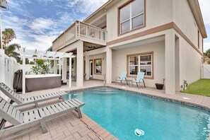 Ein zweistöckiges Haus mit Swimmingpool, Sitzgelegenheiten im Freien und einer überdachten Terrasse.