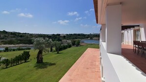 Ein Balkon mit Blick auf einen See, eine Wiese und Bäume.