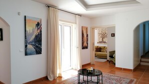 Ein großzügiges Wohnzimmer mit einem großen Fenster, einem runden Couchtisch und einem gemusterten Teppich.