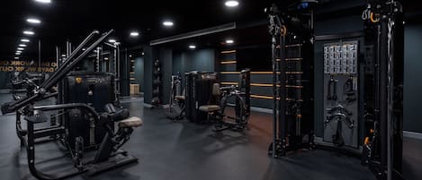 Et moderne fitnesscenter med forskellig træningsudstyr, herunder styrkemaskiner og håndvægte.