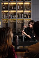 Zona de bar con estantes llenos de botellas de licores y copas.