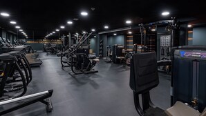 Une salle de sport équipée de tapis de course, d’appareils de musculation et d’une machine à presses pour les jambes.