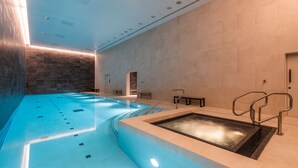 Une piscine intérieure moderne dotée d’un système de filtration à eau claire, d’une zone en contrebas et d’un banc près du mur.