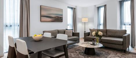 A modern living room with a dark dining table, two sofas, and a coffee table.