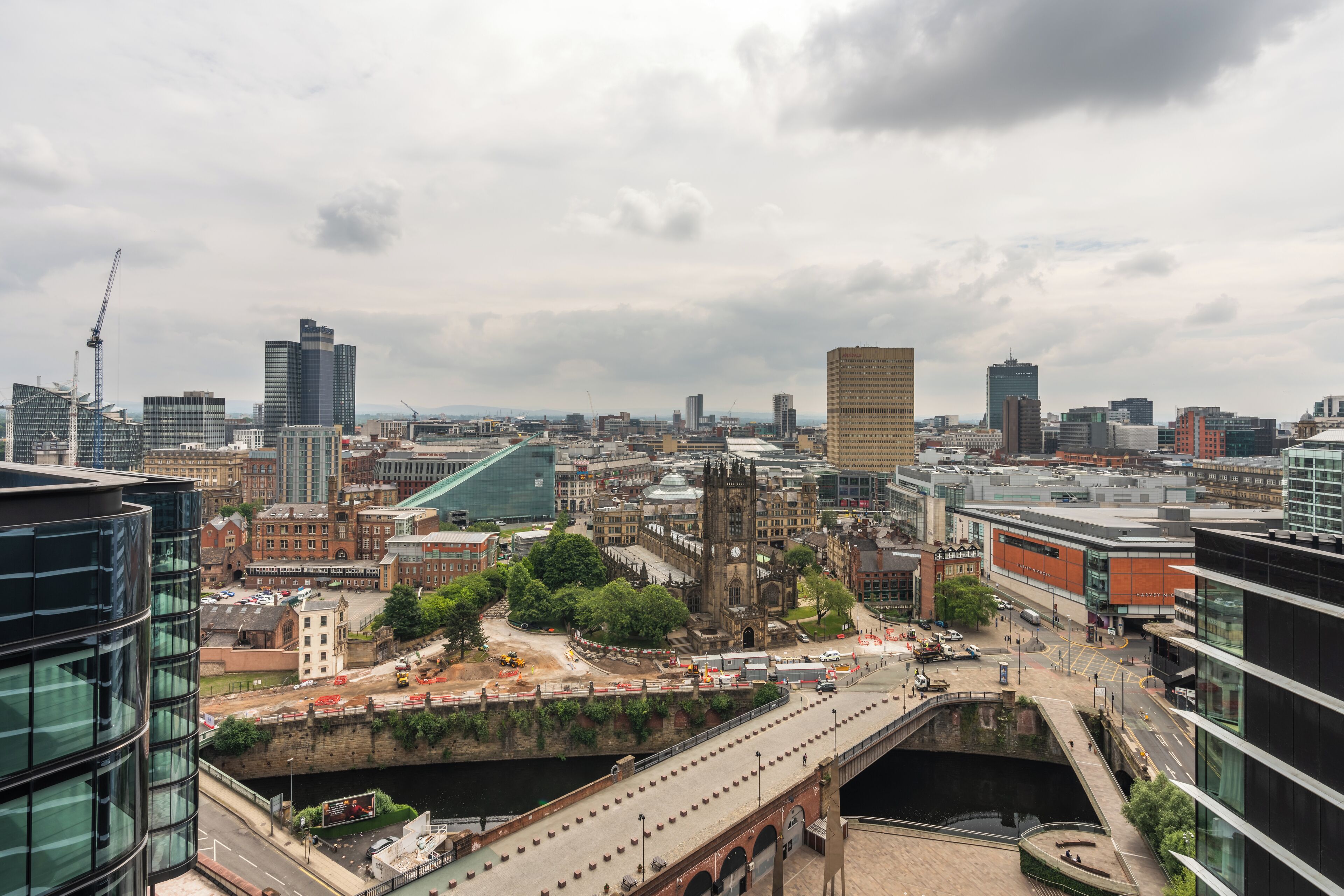 A cityscape with modern buildings, a historic church, and a bridge over a river.