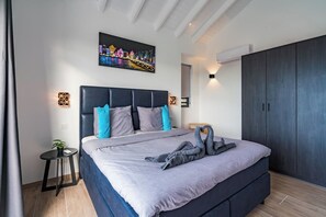 Ein modernes Schlafzimmer mit einem großen Bett, einem dunklen Kopfteil und einem Stadtbild über dem Bett.