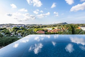Una piscina con vista a una zona residencial y colinas al lejano.