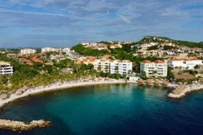 A coastal town with buildings, a beach, and a clear blue sea.