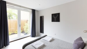 Une chambre à coucher avec un lit, une fenêtre avec des rideaux, une œuvre d’art accrochée au mur et une vue sur l’extérieur.