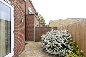 A brick house with a wooden fence, a white flowering bush, and a clear sky. - Immaculate Central Windsor Town House (Windsor)