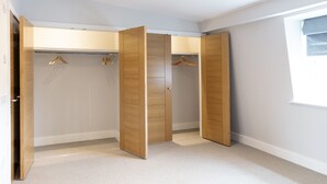 Un dressing avec des portes en bois et une tringle pour suspendre les vêtements.