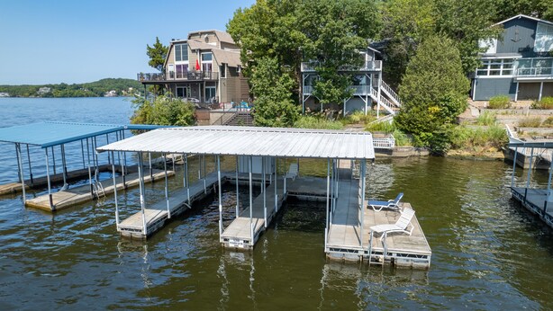 A waterfront dock with a covered seating area and a boat.