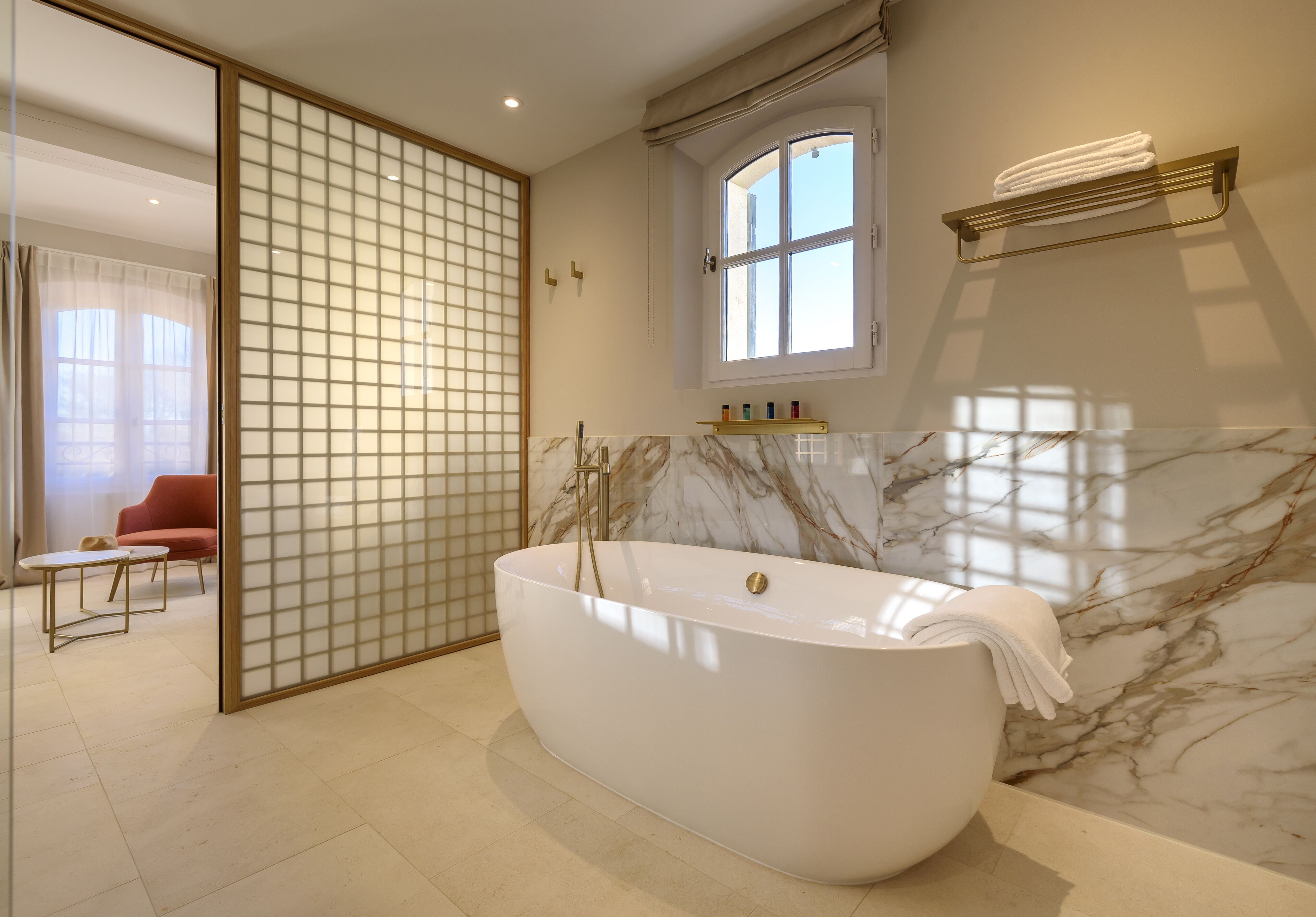 Un baño moderno con una bañera independiente, una ventana y un panel corredero shoji.