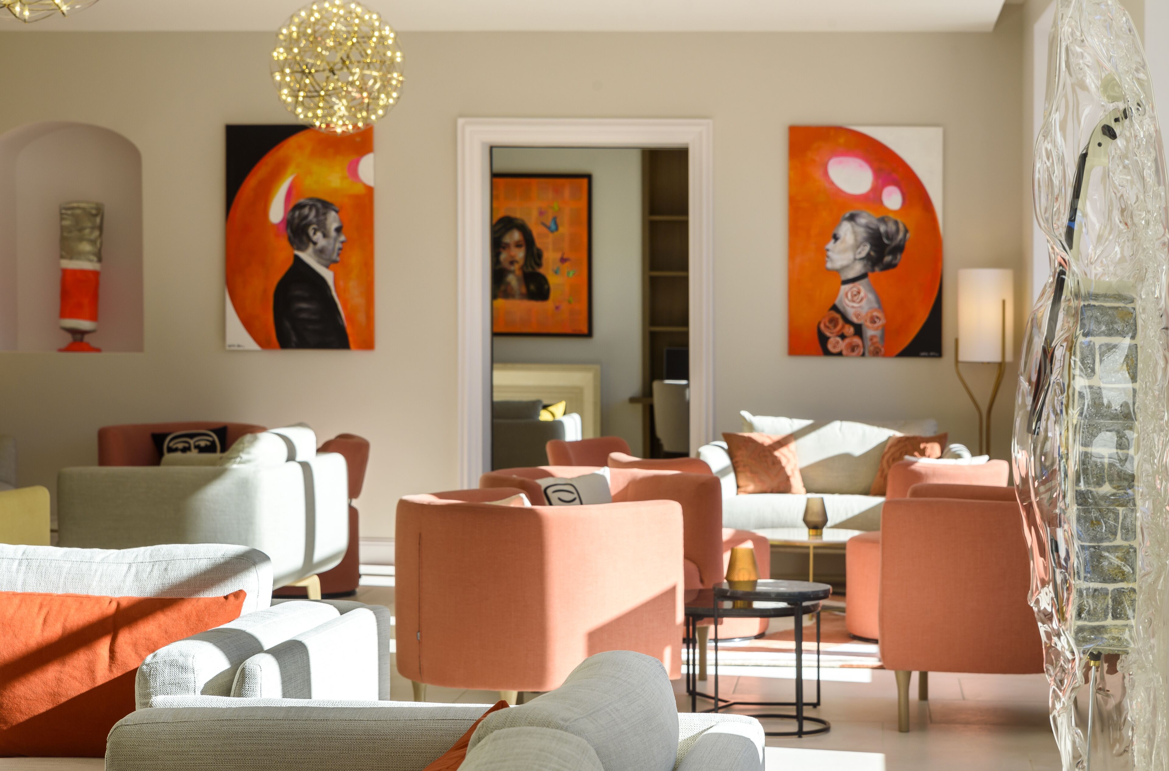 Una sala de estar moderna con muebles contemporáneos, incluyendo sofás y sillones, y dos cuadros grandes en las paredes.
