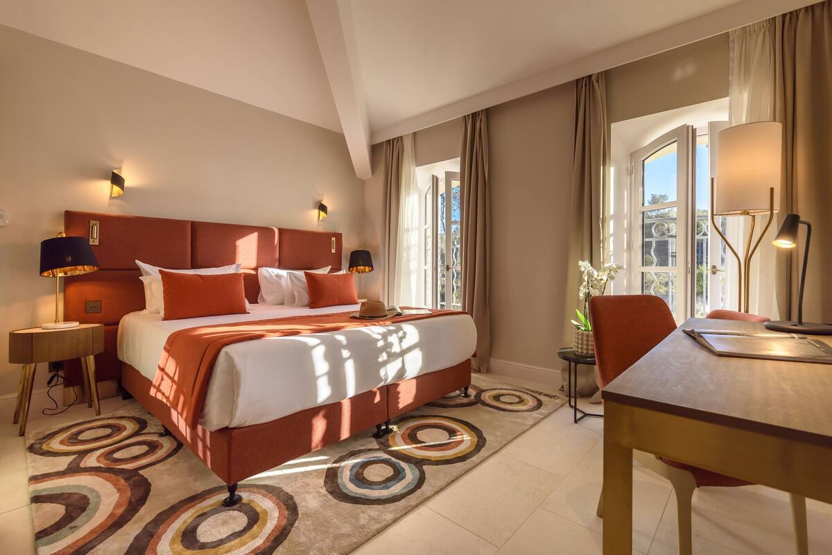 A hotel room with a large bed, two bedside tables, a desk, and a chair.