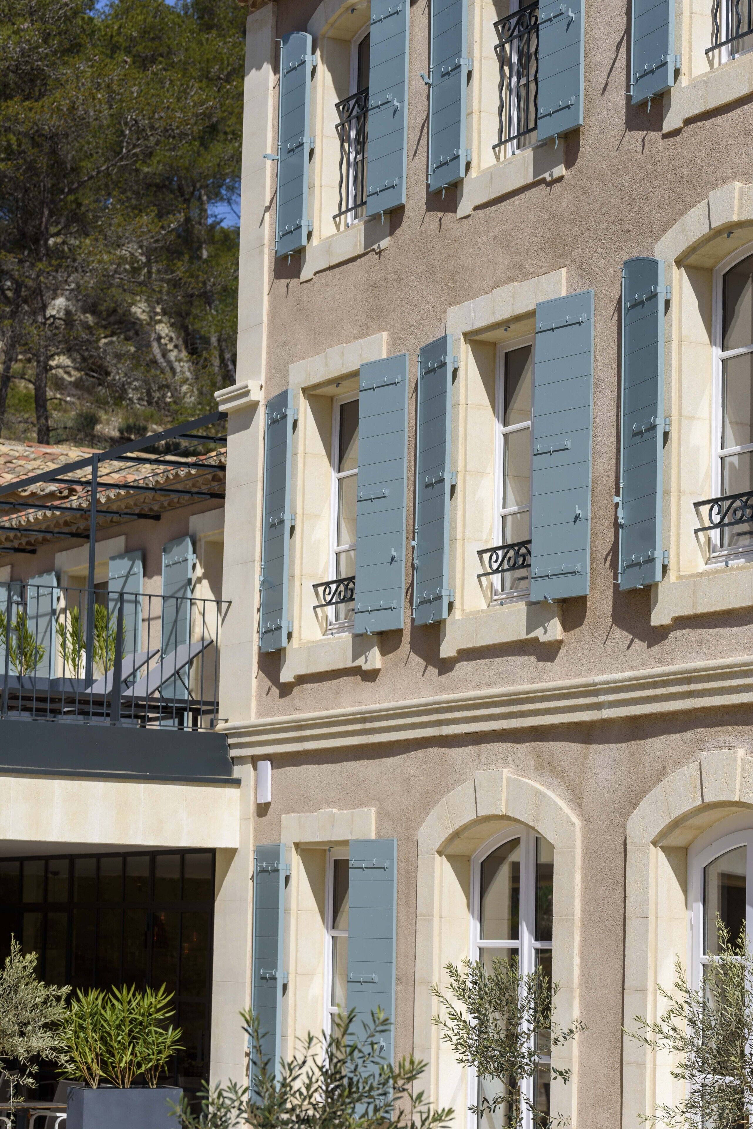 A building with multiple windows, some with shutters, and a balcony with metal railings.