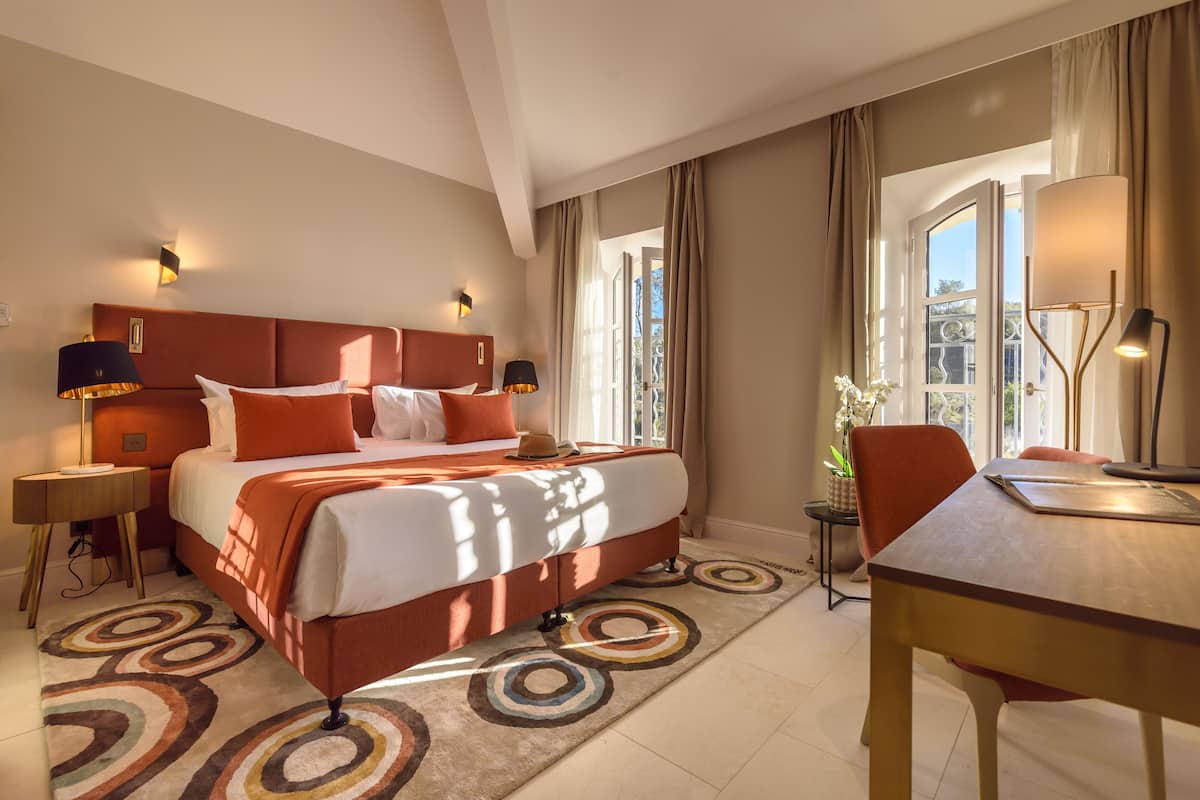 A hotel room with a large bed, a desk, and a chair.