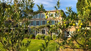 A large, multi-story building with a garden in the foreground. - Domaine de Valmouriane (St.-Rémy-de-Provence)
