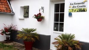 Een gebouw met een witte gevel, een zwart onderste deel en een rood dak. Er staan plantenbakken voor en een bord aan de muur.
