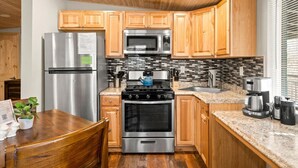 A modern kitchen with wooden cabinets, stainless steel appliances, a granite countertop, and a dining area with a wooden table and chairs. - 18 Creekside Retreat (Sedona)