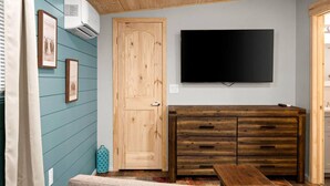 A room with a wooden door, a TV mounted on the wall, and a wooden dresser with drawers. - 18 Creekside Retreat (Sedona)