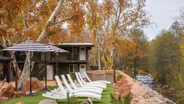A two-story building with a balcony, surrounded by autumn foliage and a river. - 17 Creekside Retreat (Sedona)