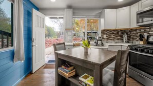 A modern kitchen with white cabinets, a central island, and a view of a landscaped garden. - 17 Creekside Retreat (Sedona)