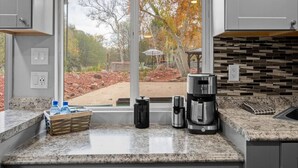 A kitchen with a large window, granite countertops, and a stone backsplash. - 17 Creekside Retreat (Sedona)
