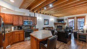 Une cuisine spacieuse avec des meubles en bois, un îlot central et une cheminée en pierre.