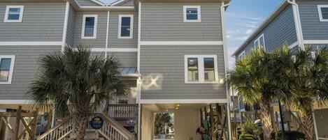 A multi-story residential building with a covered entrance and a staircase leading to the main entrance.