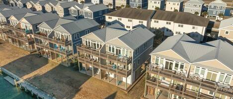 A coastal residential area with multiple two-story houses featuring balconies, a pier, and a view of the ocean.