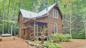 Eine Holzdiele mit Veranda, umgeben von einem Wald.
