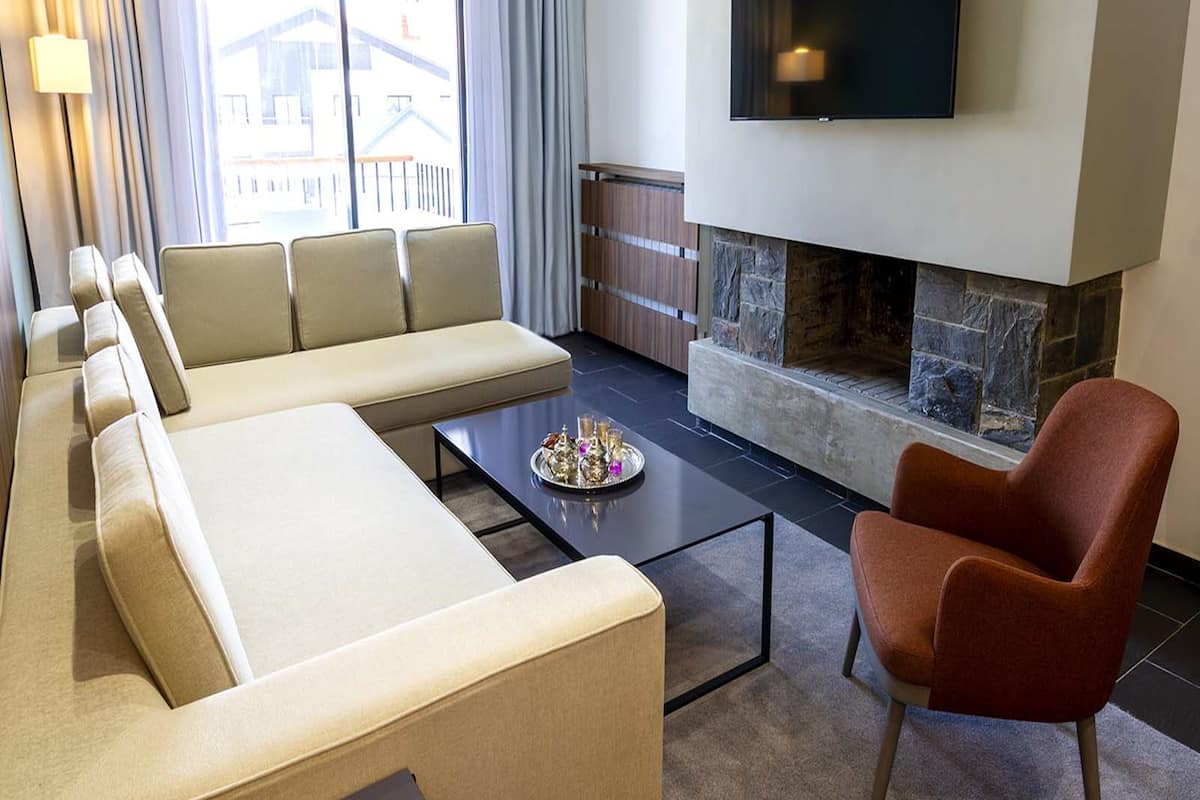 Una sala de estar moderna con un sofá, sillones, una mesa de centro, un televisor de pantalla plana y una chimenea de piedra.