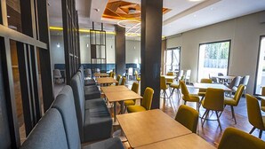 A modern dining area with long tables and booths, large windows, and a contemporary ceiling design. - Zephyr Ifrane (Ifrane)