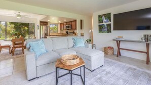 A living room with a grey sofa, a coffee table, and a TV on a stand. - Mamalahoa Mountain View Luxury Condo (Princeville)