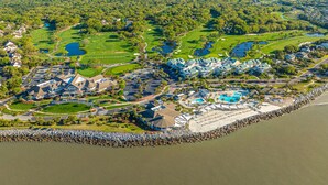 An aerial view of a coastal resort with a golf course, a large pool, and beachfront villas. - 1315 Pelican Watch Villas Beach & Free Amenities - Sale 249 USD (Seabrook Island)