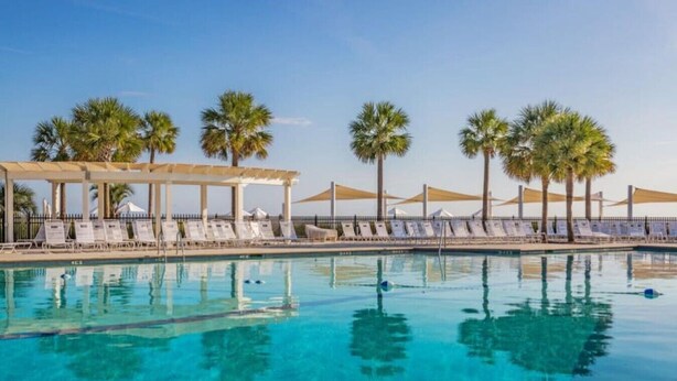 A clear blue pool with lounge chairs and palm trees. - 1315 Pelican Watch Villas Beach & Free Amenities - Sale 249 USD (Seabrook Island)