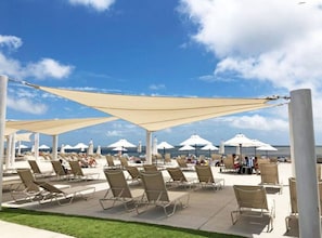 A beachside lounge area with sun loungers and umbrellas, overlooking the ocean.