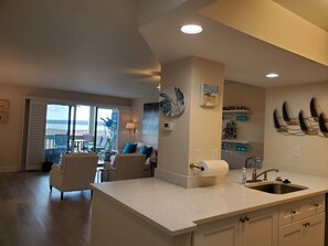 Una cocina moderna con una isla grande, un comedor con vistas y una sala de estar con sofá y sillones.