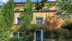 A traditional building with a stone facade, a central entrance, and a window with a grid pattern. - Villa Ocre Menerbes Panoramic view Swimming pool Garden Terraces (MENERBES)