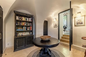 A hallway with a bookshelf, a round table with a woven basket, and a staircase leading to another room.