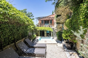 Una villa con piscina, area relax esterna e vista su una scogliera rocciosa.